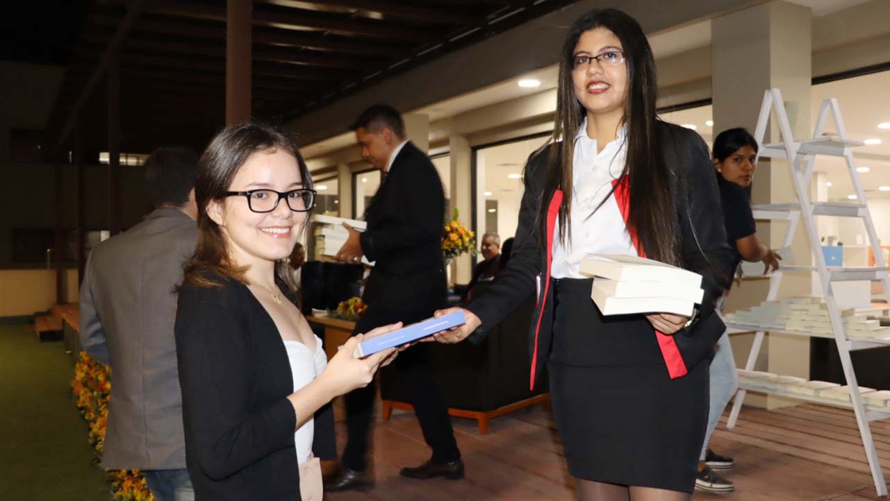 Protocolo realizando la entrega del libro a los asistentes