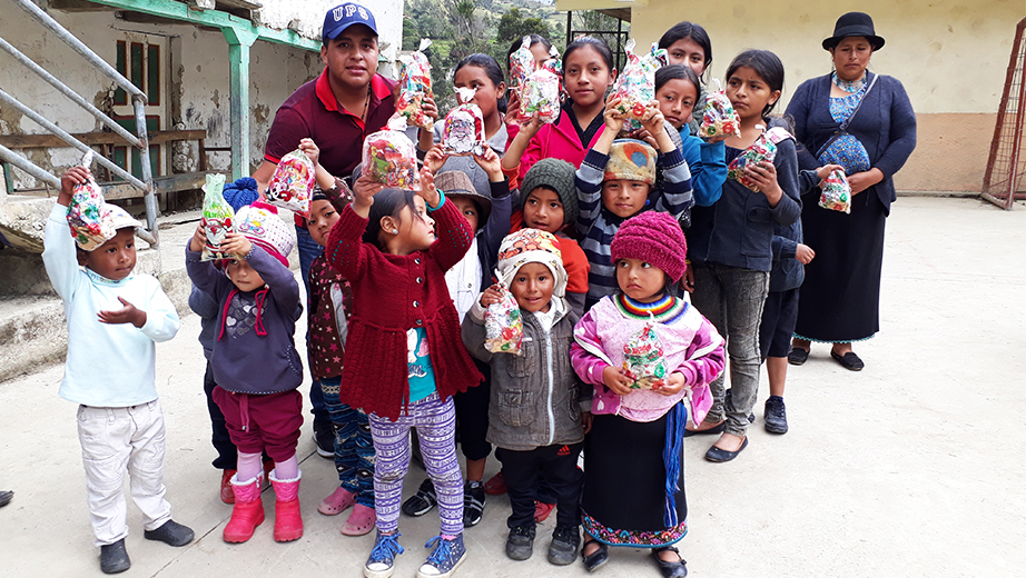 Niños y niñas de la comunidad de San Lucas en Oña (Azuay) recibiendo su funda de caramelos