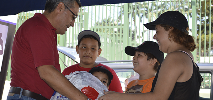 Padre Iván Segarra, Capellán de sede, recibe donaciones entregadas por varios niños.