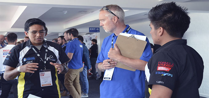 Estudiantes del equipo UPS Racing Team explicando su proyecto del prototipo de fórmula SAE a los miembros del jurado calificador de los organizadores