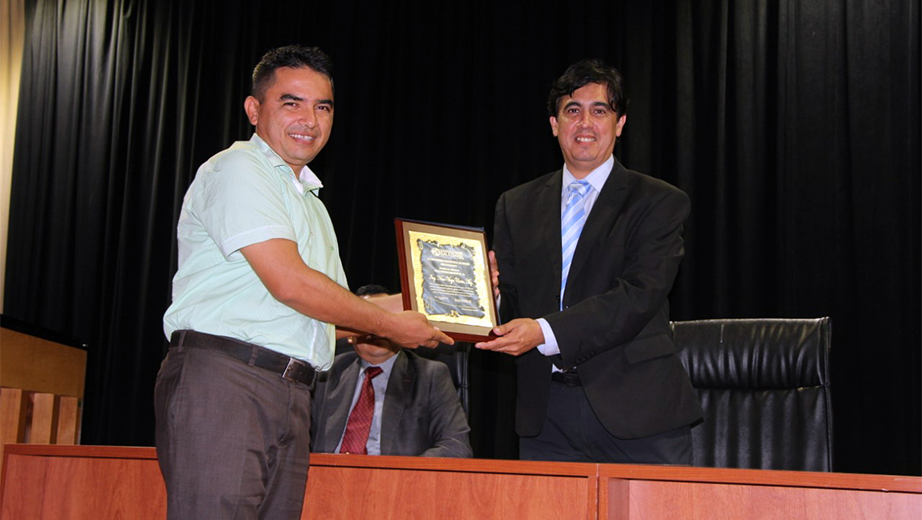 Andrés Bayolo awarding a recognition plaque