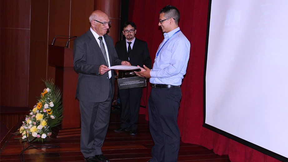 El Rector de la UPS, P. Javier Herrán Gómez, entrega del primer premio al ganador del concurso de los mejores trabajos de accesibilidad Julián Noguera de Colombia