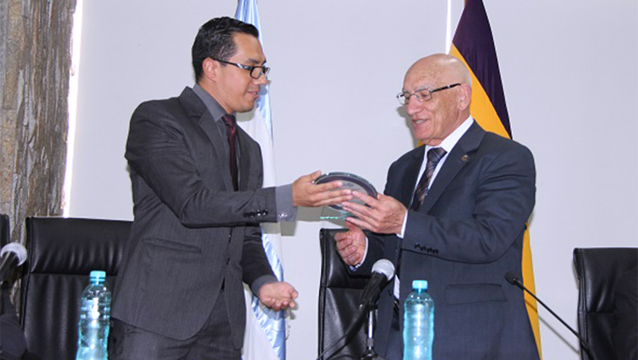 MSc. Renato Fierro realizando la entrega de placa la PhD. Javier Herrán