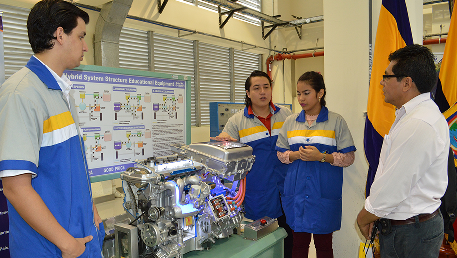 Estudiantes de Ing. Automotriz de la UPS sede Guayaquil con un transmisor de motor híbrido.