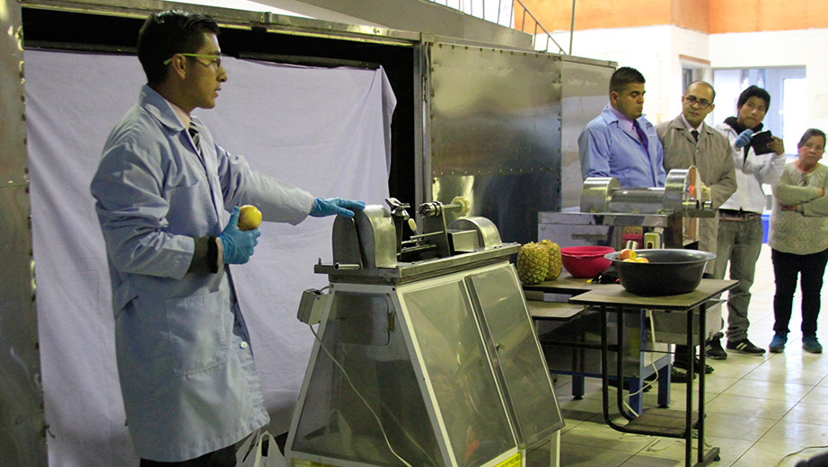 Estudiantes Jimmy Leiton y Diego Meneses presentan a la comunidad la máquina peladora y picadora de fruta.