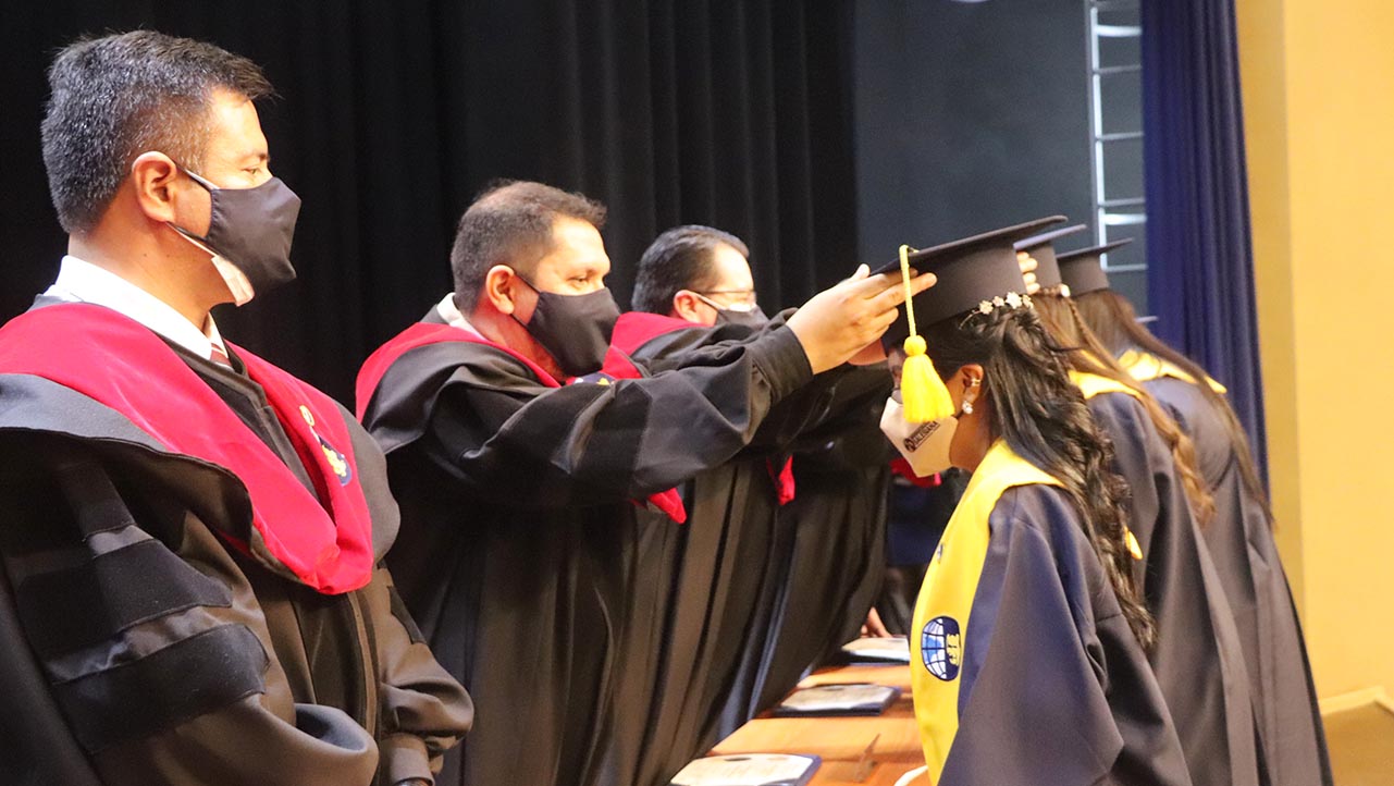 Raúl Álvarez, Vicerrector de la sede Guayaquil, coloca el birrete a una de las graduadas
