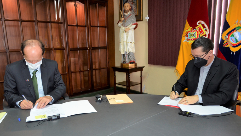 Captan el momento que el Embajador… y el Padre Juan Cárdenas Tapia, Rector de la UPS sellan el acuerdo con su firma.